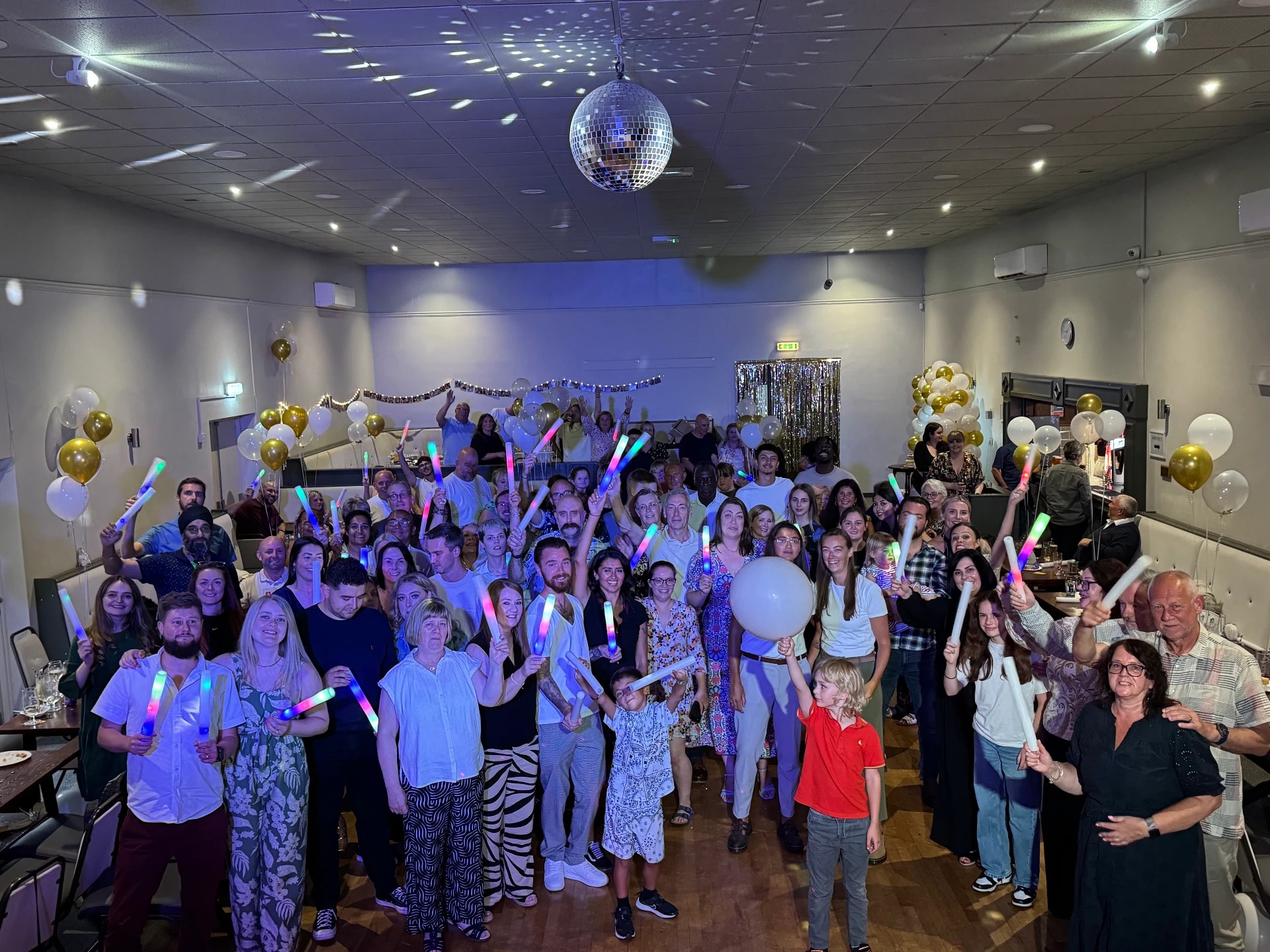 Wedding party guests celebrating with LED glow sticks and balloons